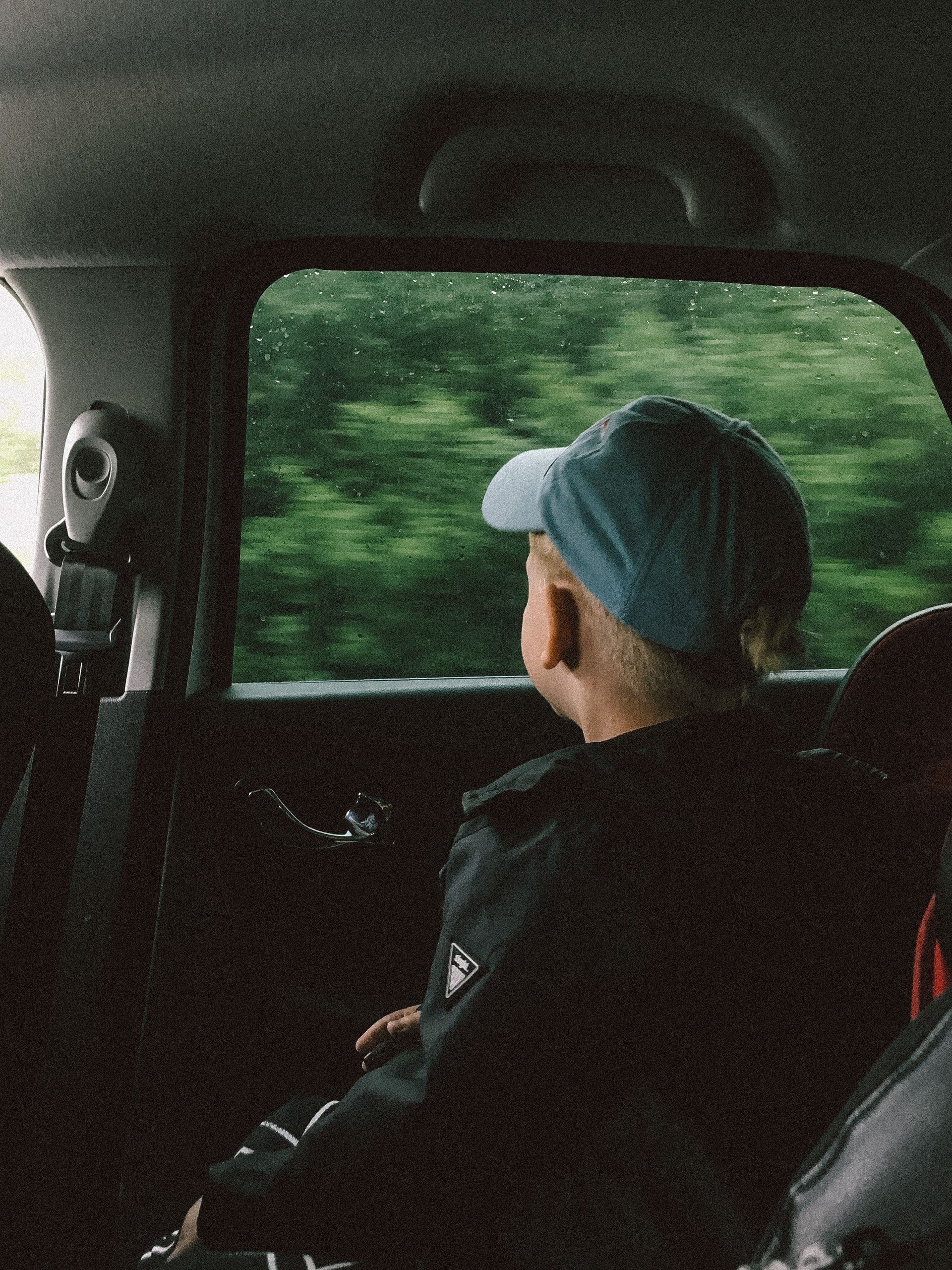 A child looking out the car window as the scenery blurs past