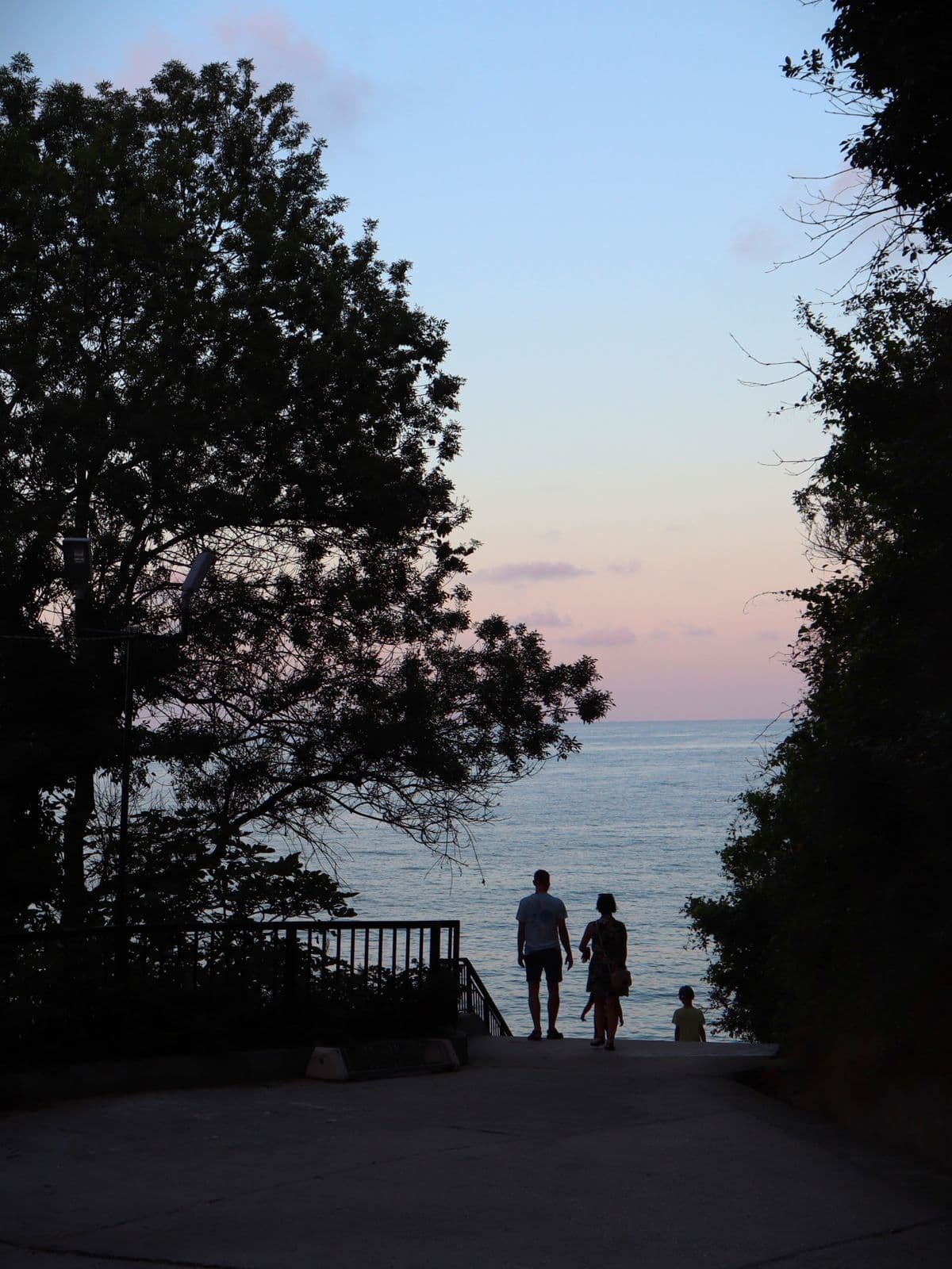 A family silhouetted against the ocean at sunset
